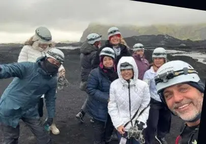 Grupo de viajeros con cascos en un campo de lava de arena negra